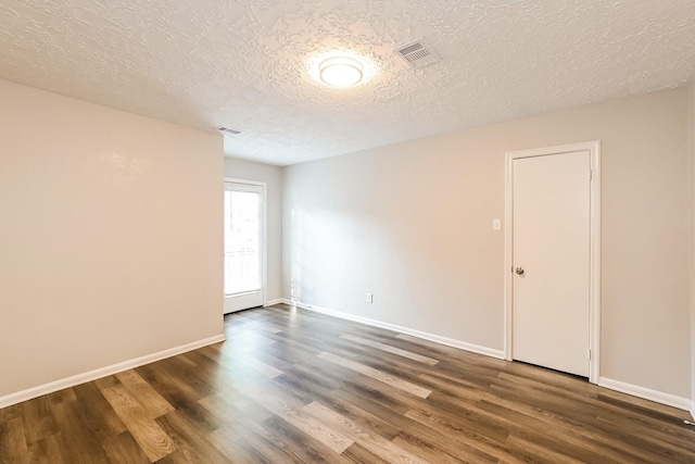 unfurnished room featuring visible vents, baseboards, a textured ceiling, and dark wood finished floors