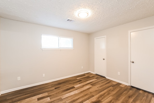 unfurnished bedroom with a textured ceiling and dark hardwood / wood-style flooring