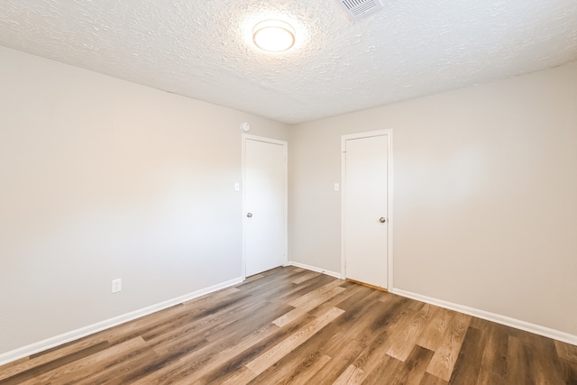 unfurnished room with a textured ceiling and hardwood / wood-style floors