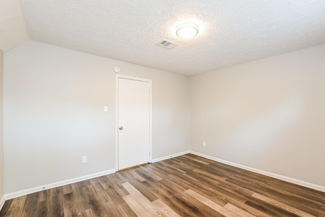 unfurnished room featuring a textured ceiling, wood finished floors, baseboards, and visible vents