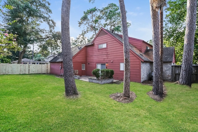 view of side of home featuring fence, a shingled roof, and a lawn