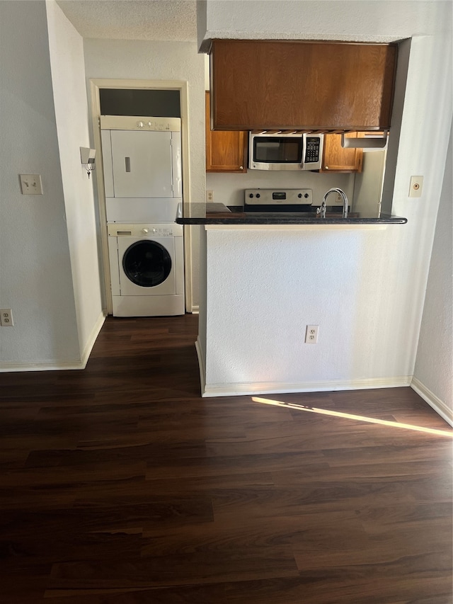 kitchen featuring dark hardwood / wood-style floors, white range oven, sink, stacked washer / dryer, and a textured ceiling