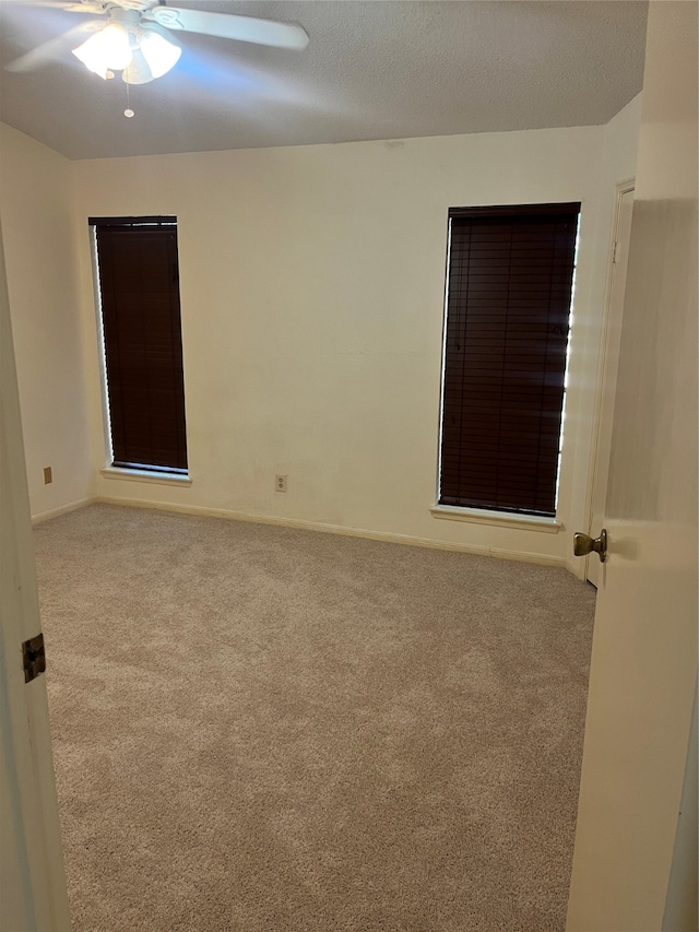 carpeted spare room with a textured ceiling and ceiling fan