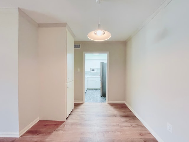 hallway with light wood-type flooring and ornamental molding