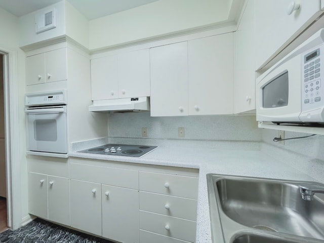 kitchen with white appliances, white cabinetry, and sink