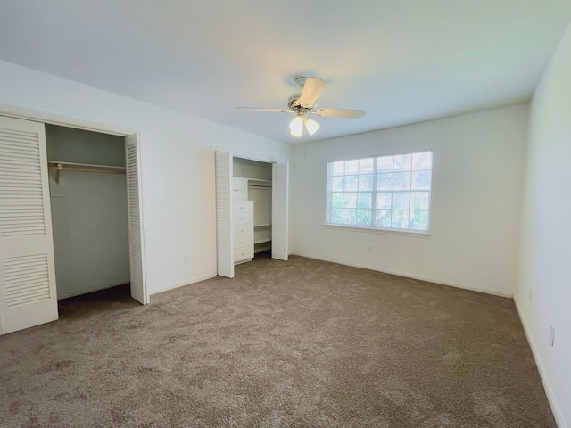 unfurnished bedroom with ceiling fan, multiple closets, and carpet flooring