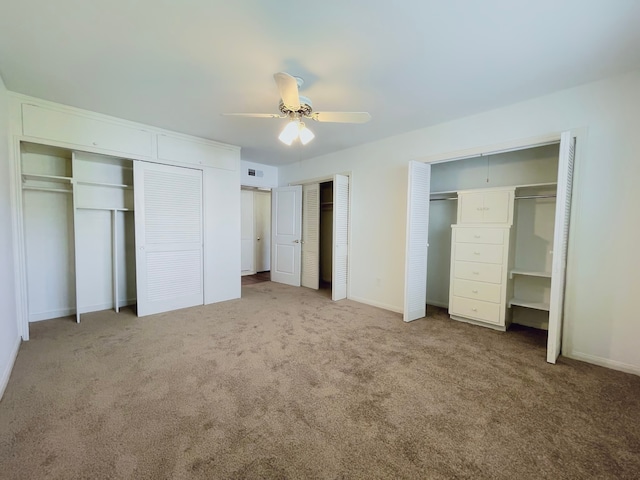 unfurnished bedroom with multiple closets, ceiling fan, and carpet flooring