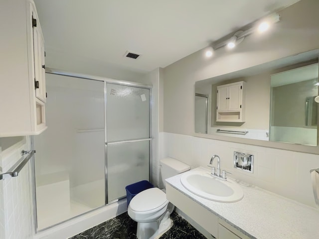 bathroom with backsplash, a shower with door, vanity, and toilet