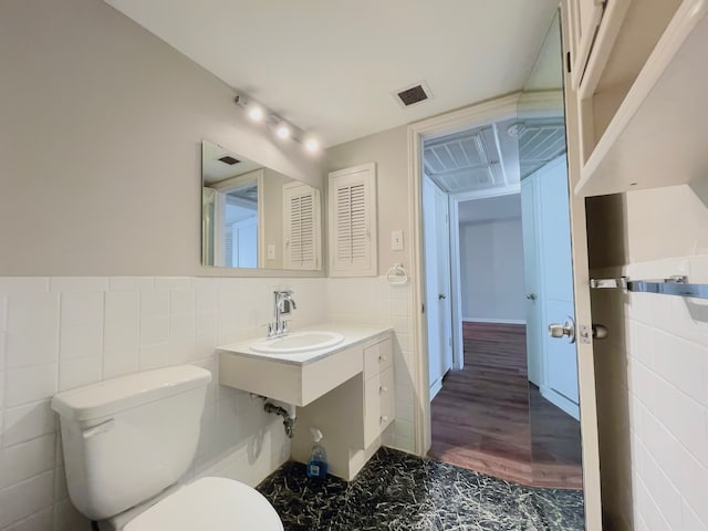 bathroom with tile walls, sink, hardwood / wood-style floors, and toilet