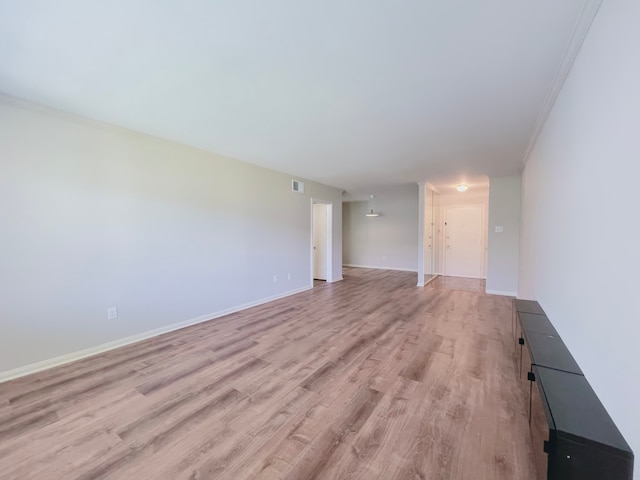 unfurnished living room with crown molding and light hardwood / wood-style floors