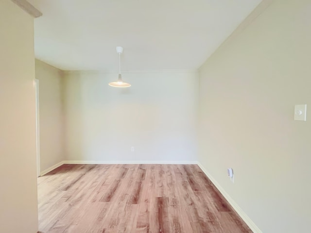 empty room featuring light wood-type flooring and crown molding