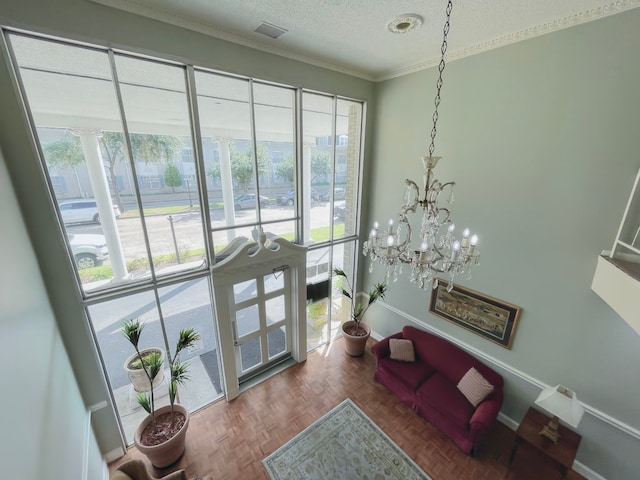 interior space with a textured ceiling, parquet flooring, ornamental molding, and a healthy amount of sunlight