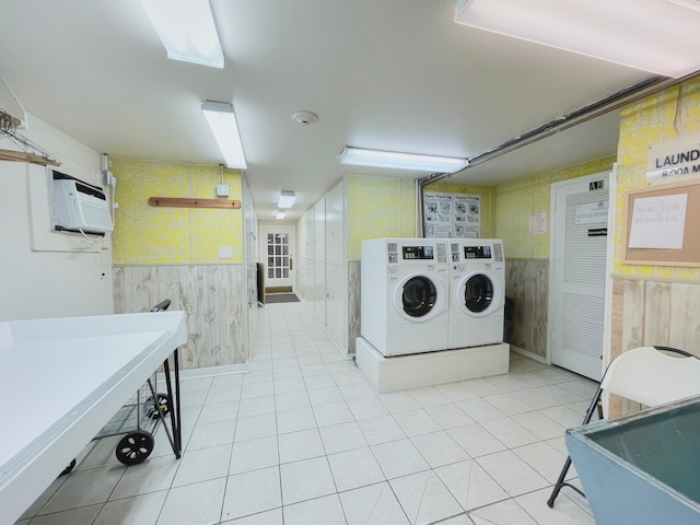 washroom featuring washer and clothes dryer, wooden walls, light tile patterned floors, and an AC wall unit