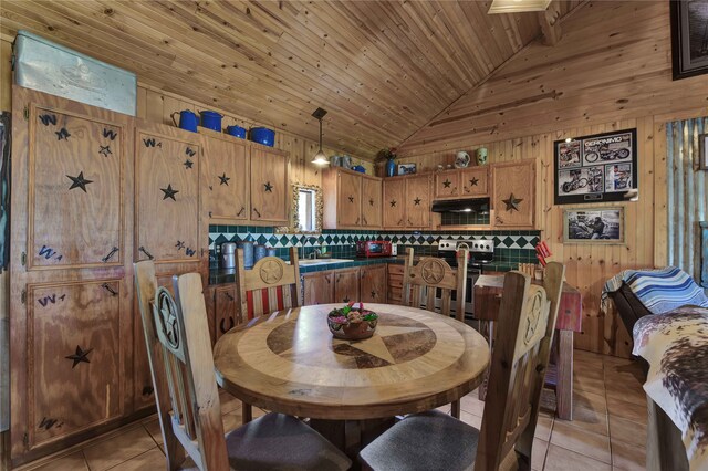 dining area featuring wood ceiling, sink, light tile patterned floors, wooden walls, and high vaulted ceiling