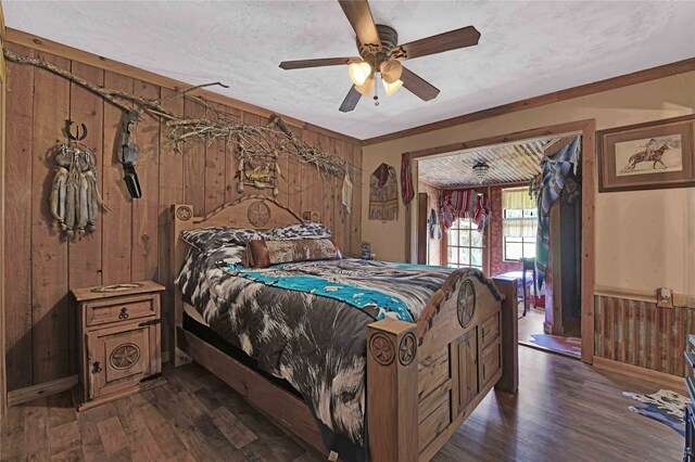 bedroom featuring wooden walls, ceiling fan, dark wood-type flooring, and a textured ceiling