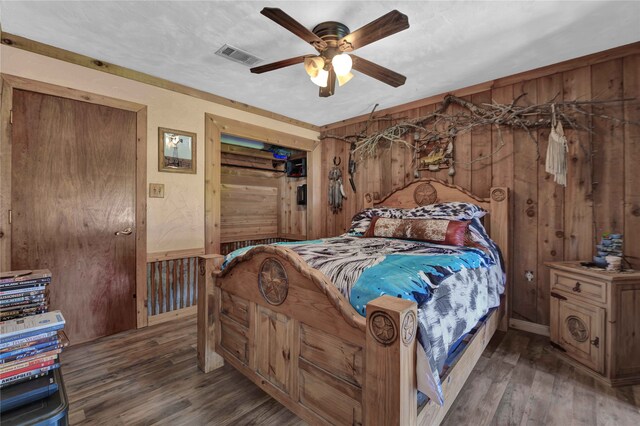 bedroom with ceiling fan, wooden walls, and dark hardwood / wood-style flooring