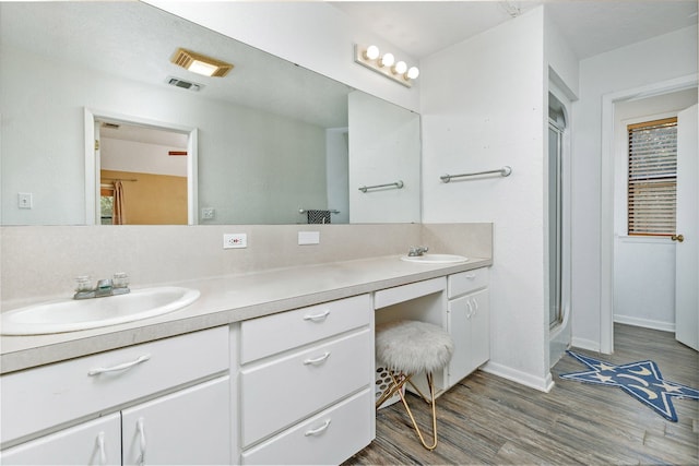 bathroom with wood-type flooring, vanity, and combined bath / shower with glass door