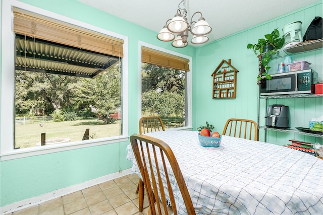 tiled dining area featuring a healthy amount of sunlight and an inviting chandelier