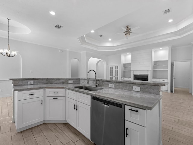 kitchen with ceiling fan with notable chandelier, sink, stainless steel dishwasher, a tray ceiling, and white cabinetry