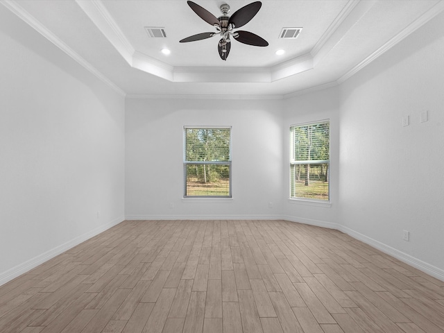 unfurnished room with a raised ceiling, crown molding, and light hardwood / wood-style floors