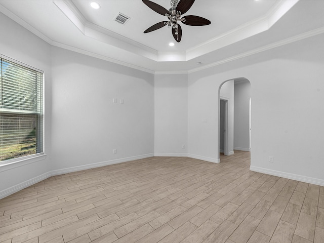 empty room with a tray ceiling, plenty of natural light, and ornamental molding