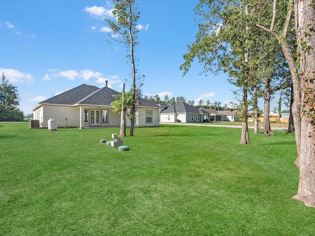 view of yard featuring central AC and french doors