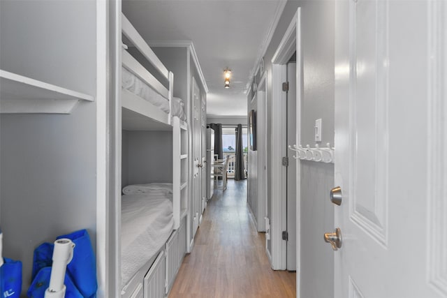 hall with light wood-style floors and crown molding