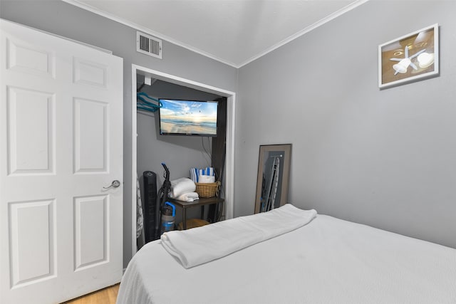 bedroom featuring wood finished floors, visible vents, and crown molding