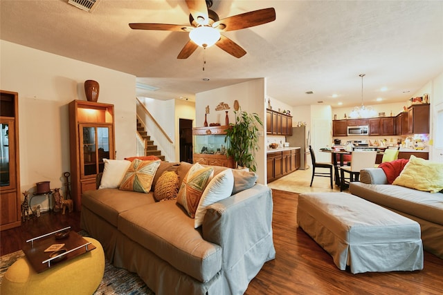 living area with a ceiling fan, stairs, wood finished floors, and visible vents