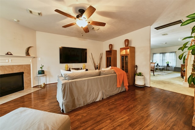 bedroom featuring ceiling fan, hardwood / wood-style flooring, and a tiled fireplace