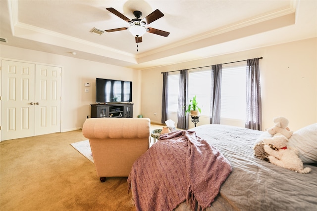 bedroom featuring a raised ceiling, ornamental molding, ceiling fan, and light colored carpet