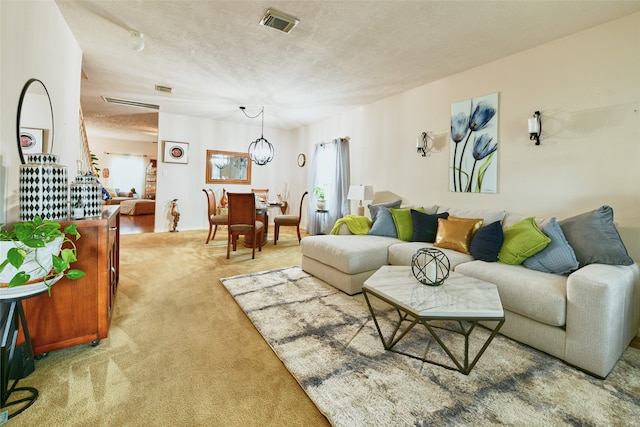 carpeted living room featuring a textured ceiling and a notable chandelier