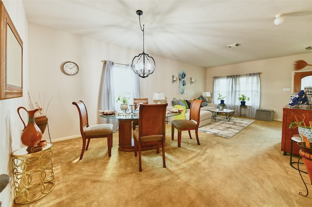 dining area with an inviting chandelier and light carpet