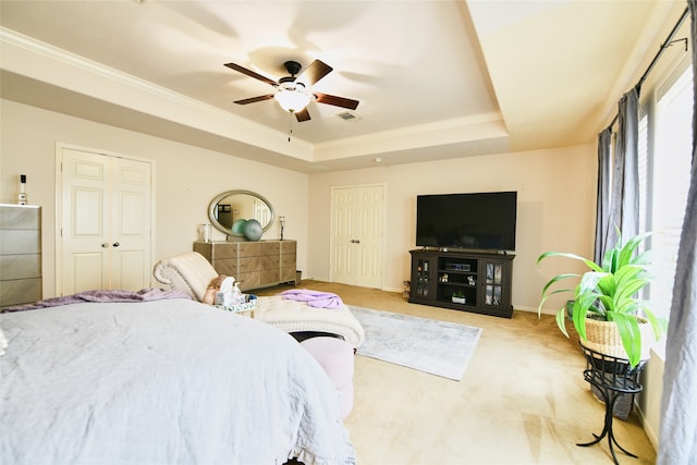 carpeted bedroom with ceiling fan, a tray ceiling, and crown molding