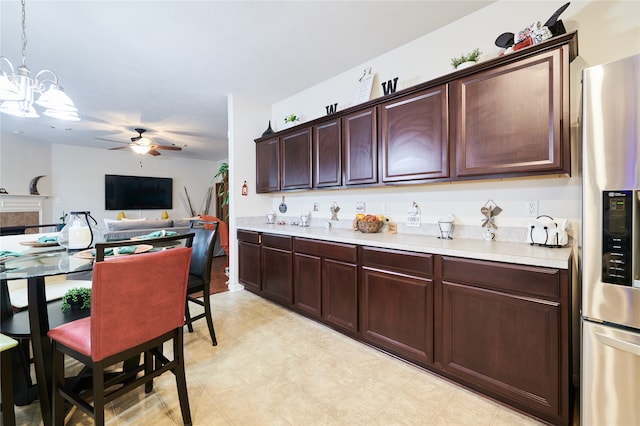 kitchen featuring ceiling fan with notable chandelier, dark brown cabinets, stainless steel fridge with ice dispenser, and decorative light fixtures