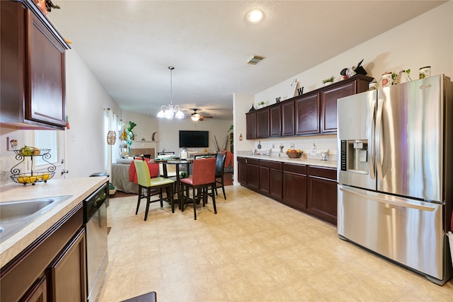 kitchen with ceiling fan with notable chandelier, dark brown cabinets, appliances with stainless steel finishes, and decorative light fixtures