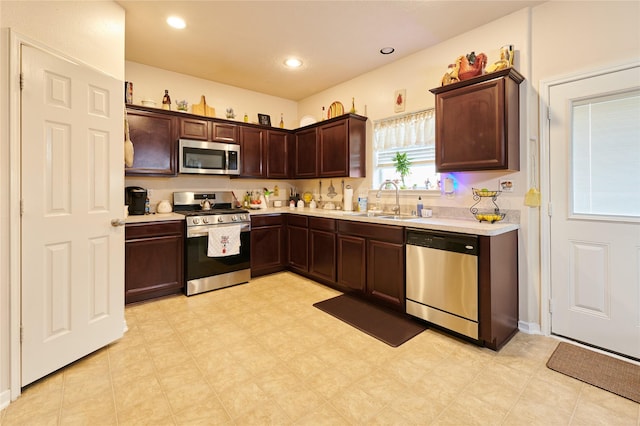 kitchen featuring light countertops, dark brown cabinetry, appliances with stainless steel finishes, and a sink