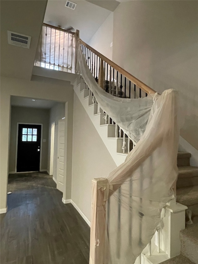 staircase with hardwood / wood-style flooring and a high ceiling