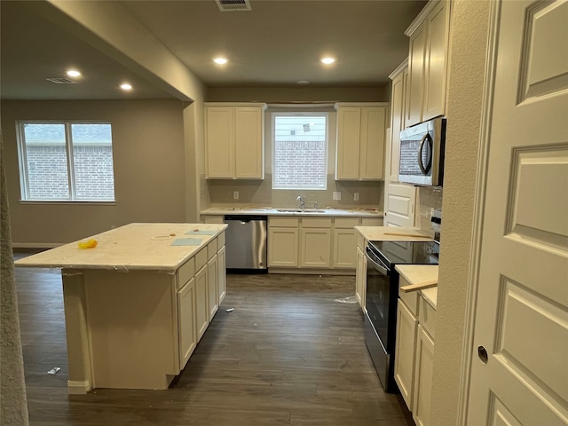 kitchen with sink, a kitchen island, dark hardwood / wood-style flooring, white cabinets, and appliances with stainless steel finishes