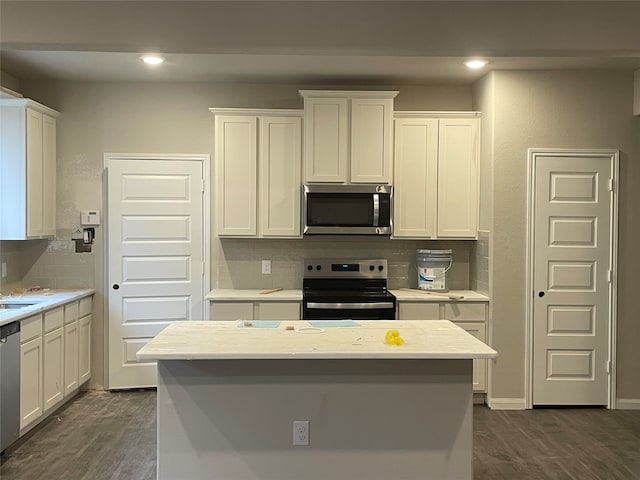 kitchen with dark hardwood / wood-style floors, white cabinetry, backsplash, and appliances with stainless steel finishes