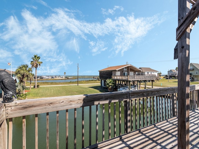 wooden terrace with a yard and a water view