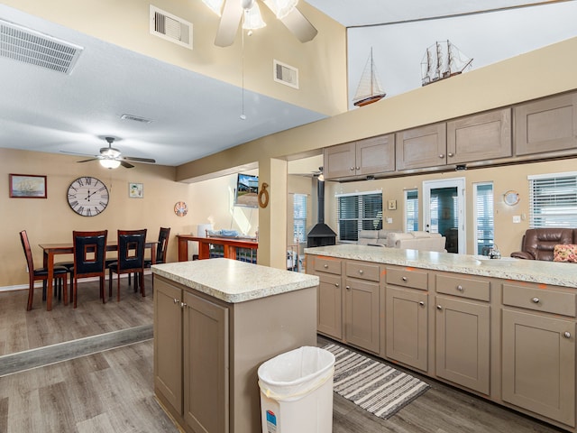 kitchen with hardwood / wood-style floors, ceiling fan, a high ceiling, and a kitchen island