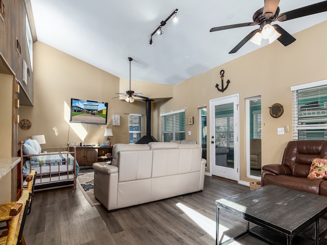 living room with dark wood-type flooring, vaulted ceiling, a wood stove, and ceiling fan