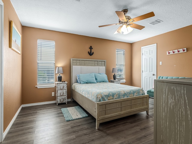 bedroom featuring dark wood-type flooring, ceiling fan, and a textured ceiling