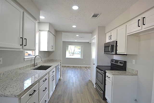 kitchen featuring wood-type flooring, white cabinetry, sink, and appliances with stainless steel finishes