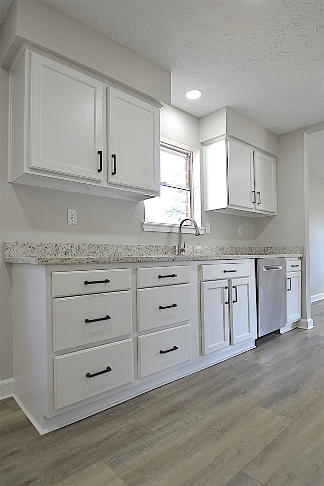 kitchen with white cabinets, dishwasher, light wood-type flooring, and a textured ceiling