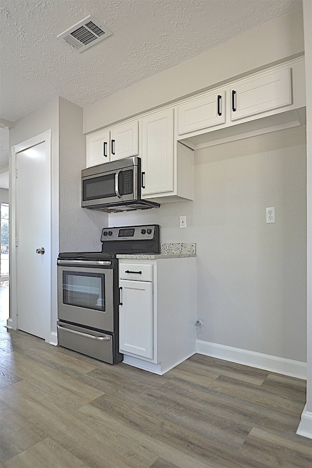 kitchen featuring white cabinets, light wood-type flooring, and stainless steel appliances