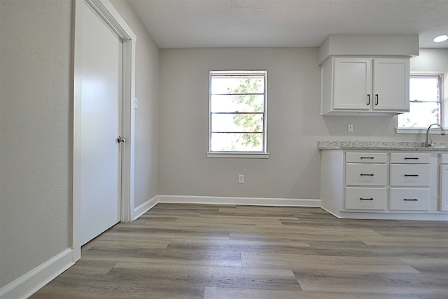 unfurnished dining area with a textured ceiling, light wood-type flooring, and sink