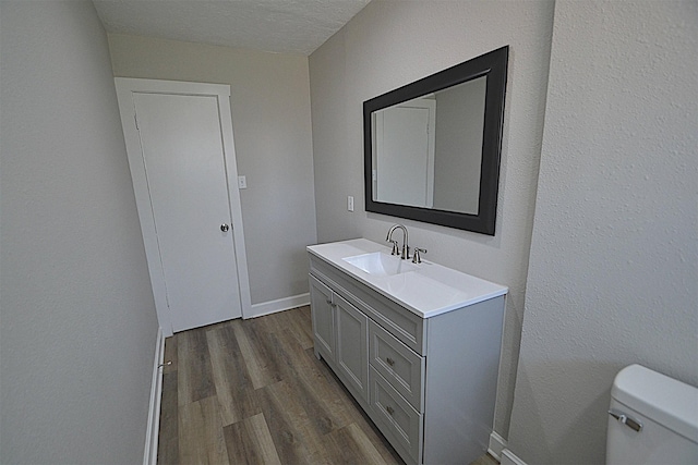 bathroom with vanity, wood-type flooring, a textured ceiling, and toilet