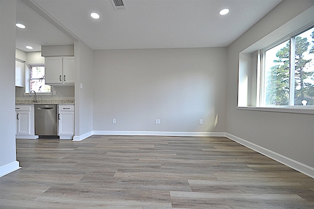 kitchen with white cabinets, light wood-type flooring, plenty of natural light, and dishwasher